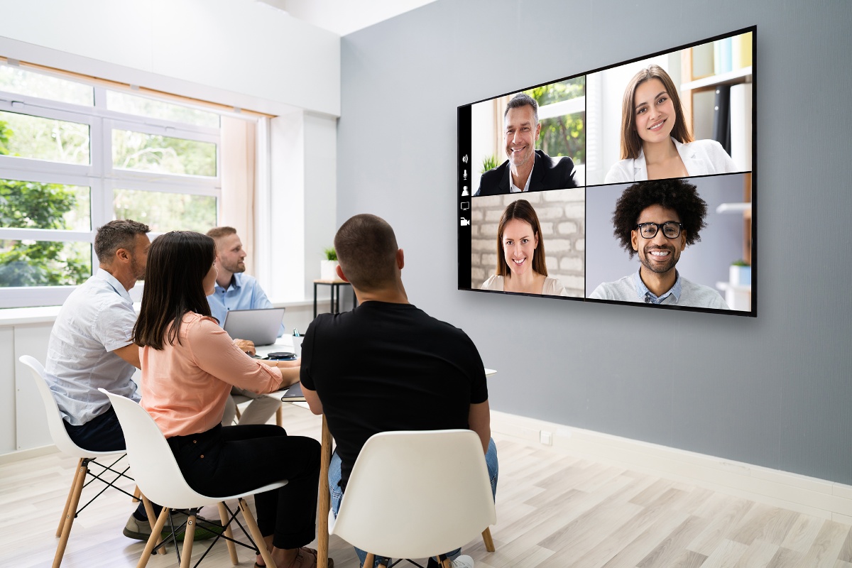 Illustrasjonsbilde av mennersker som sitter i møterom med videokonferanse.